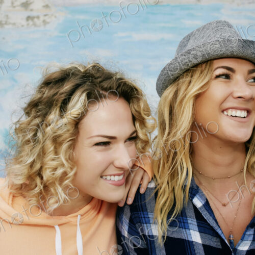 Two smiling young women, one wearing grey Trilby hat Two smiling young women, one wearing grey Trilby hat