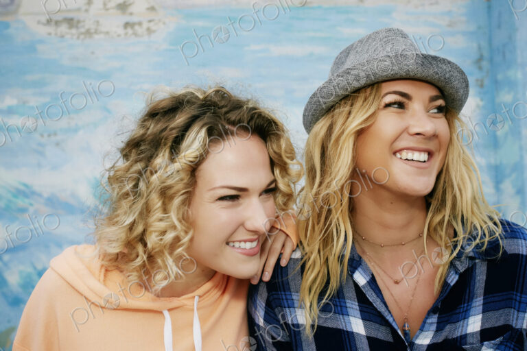 Two smiling young women, one wearing grey Trilby hat