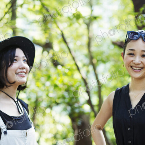 Two smiling young women standing in a forest.