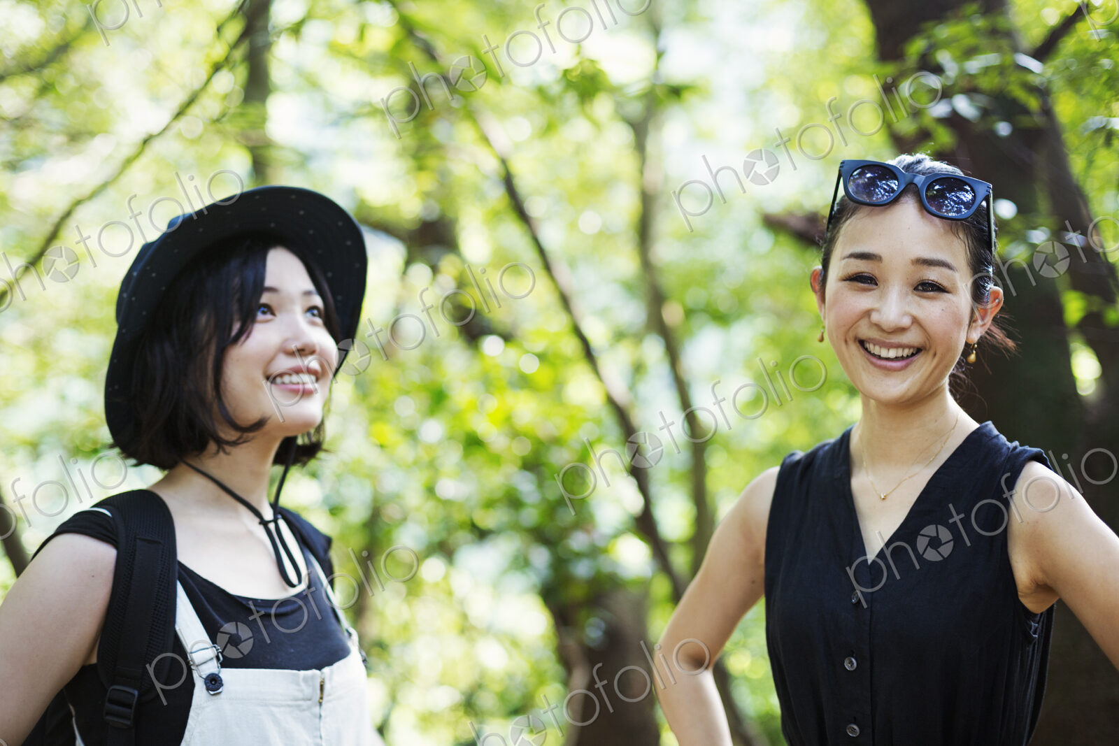 Two smiling young women standing in a forest.