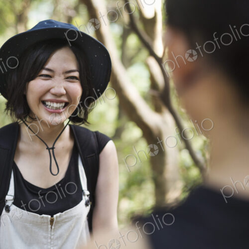 Two smiling young women standing in a forest.