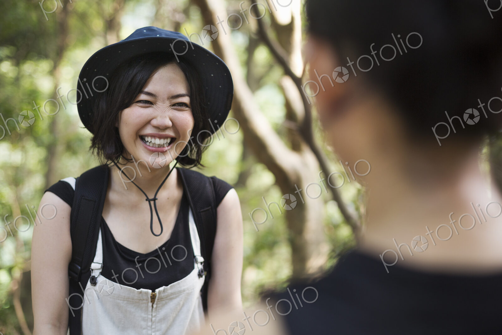 Two smiling young women standing in a forest.