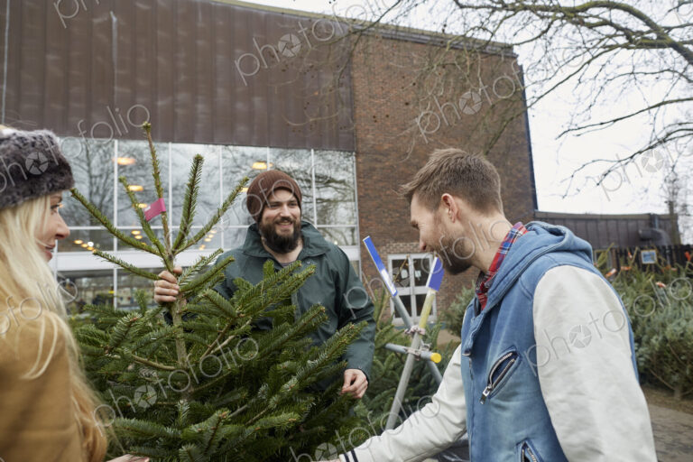 Two staff and a woman client looking at a large Christmas tree.