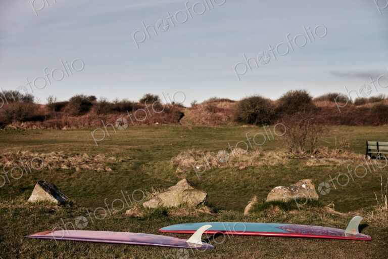 Two surf boards lying on grass near the beach