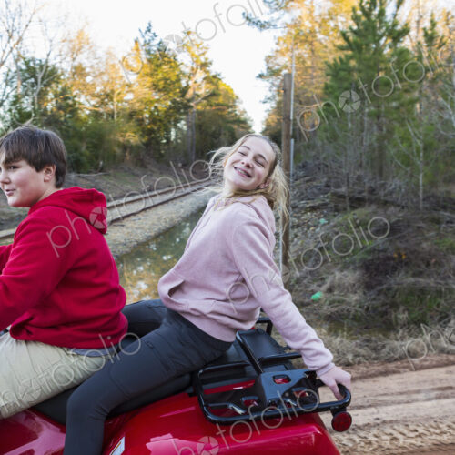 Two teenagers riding on a buggy, all terrain vehicle on a muddy track. Two teenagers riding on a buggy, all terrain vehicle on a muddy track.
