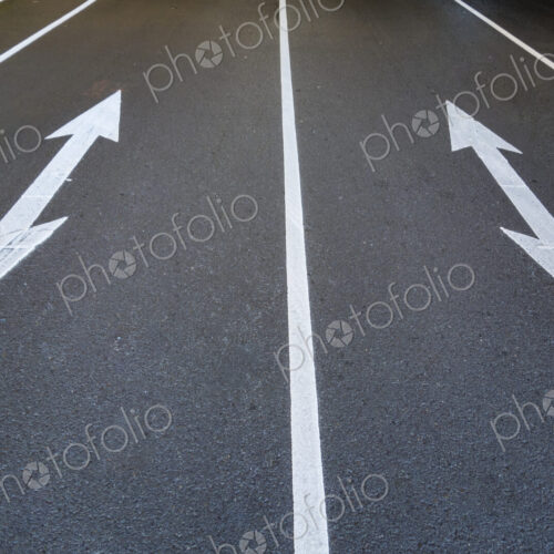 Two traffic arrow symbols on the road surface, pointed at both ends, on a city road in… Two traffic arrow symbols on the road surface, pointed at both ends, on a city road in…