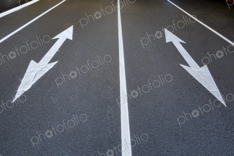 Two traffic arrow symbols on the road surface, pointed at both ends, on a city road in…