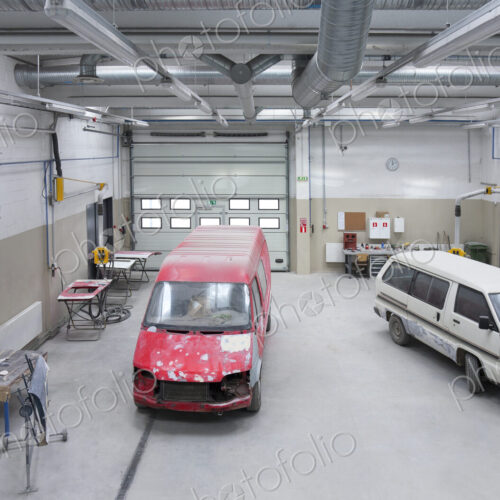 Two vans in a large repair workshop or garage. Two vans in a large repair workshop or garage.