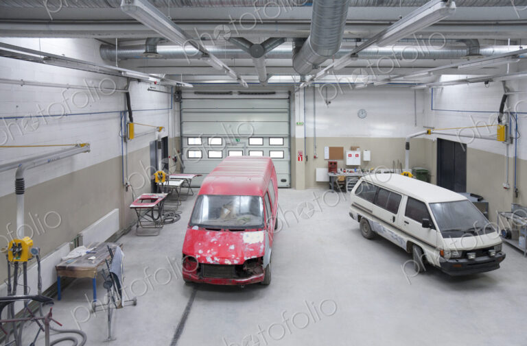Two vans in a large repair workshop or garage.