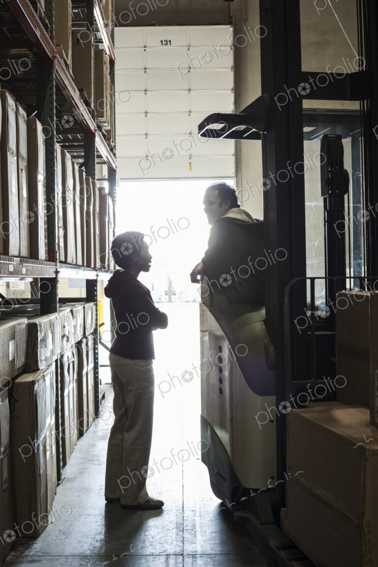 Two warehouse employees talking over an issue while working in a distribution warehouse.