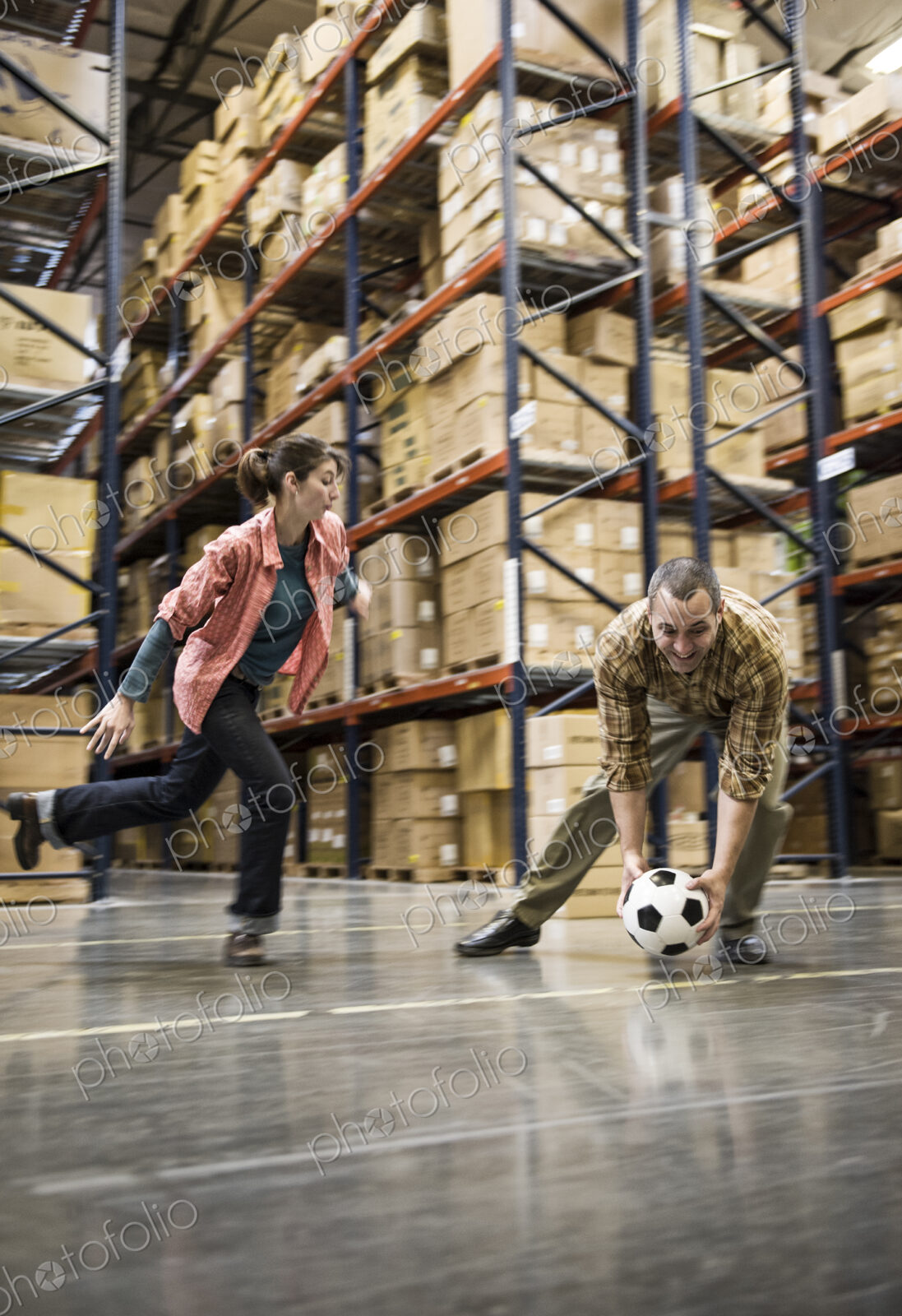 Two warehouse workers playing soccer during a work break in a distribution warehouse.
