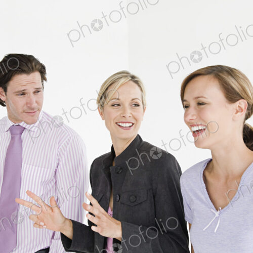 Two woman and a man wearing professional clothing talking and smiling.