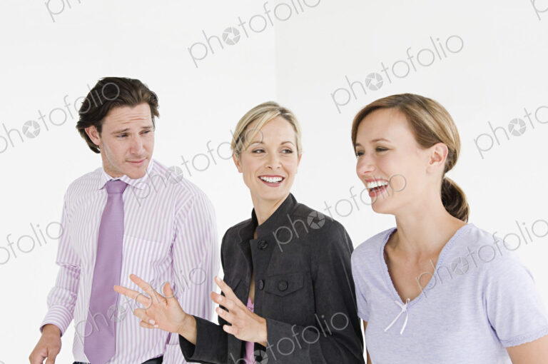 Two woman and a man wearing professional clothing talking and smiling.