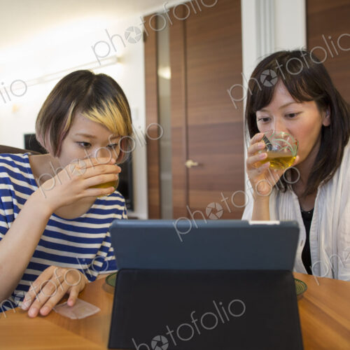 Two woman seated looking at a laptop computer or digital tablet.
