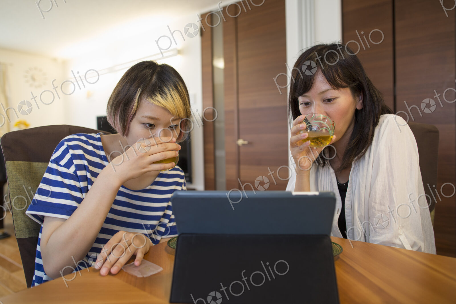 Two woman seated looking at a laptop computer or digital tablet.