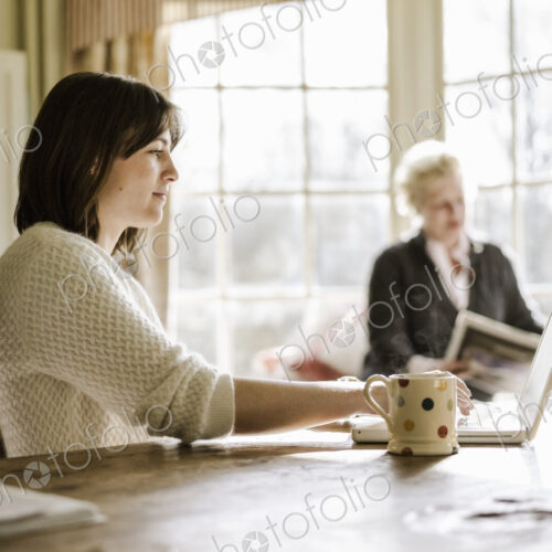 Two women at home seated at a kitchen table, mother and daughter Two women at home seated at a kitchen table, mother and daughter