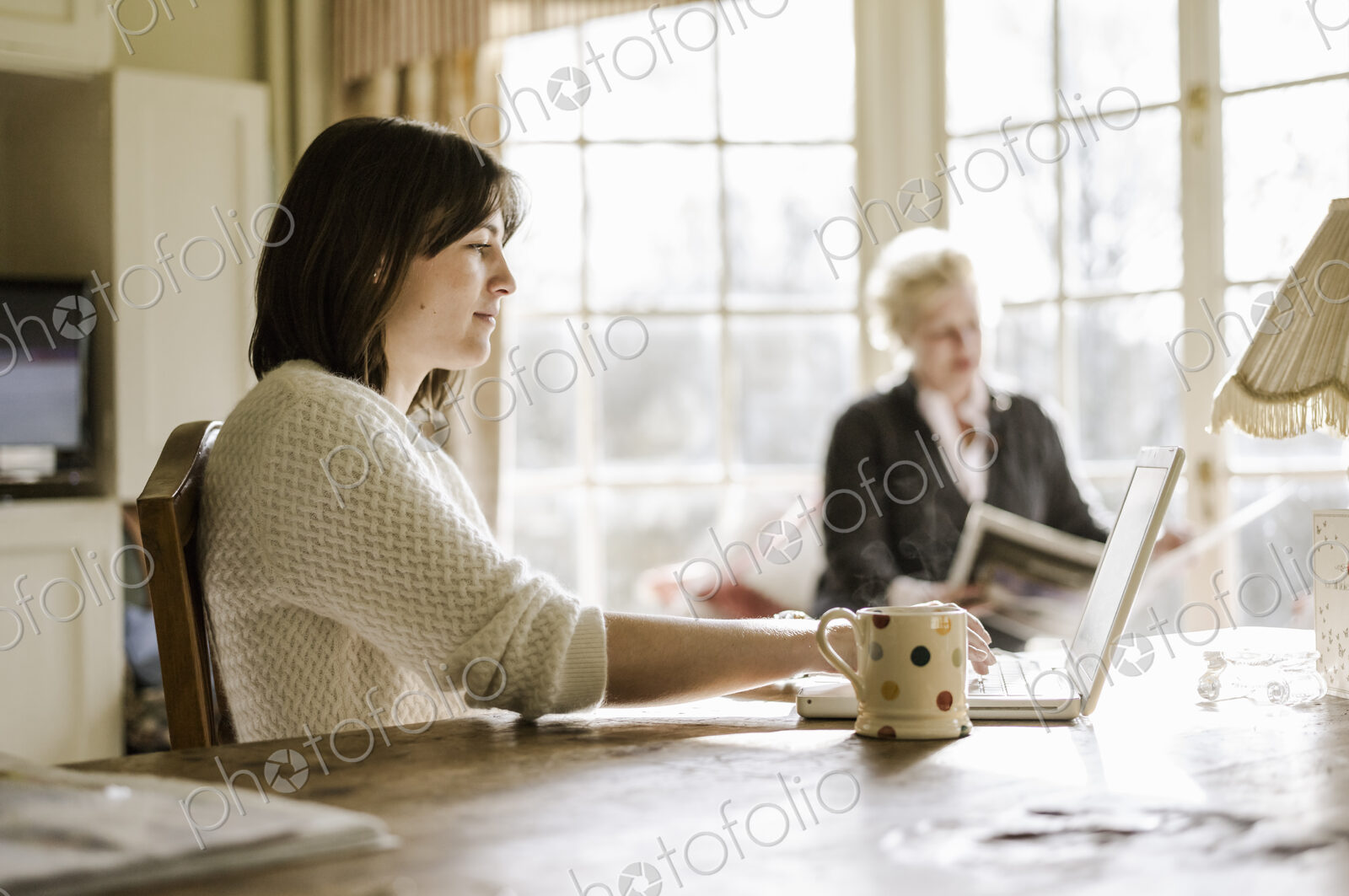 Two women at home seated at a kitchen table, mother and daughter
