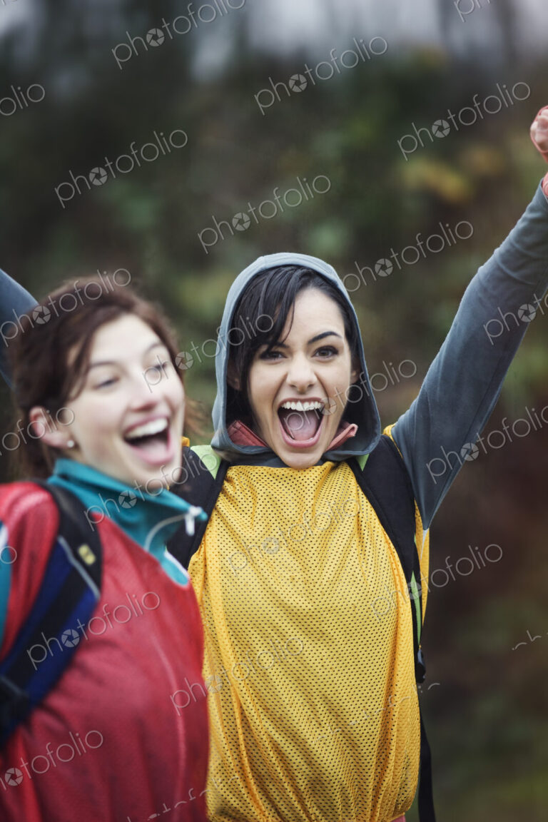 Two women cheering at an informal outdoor sporting event.