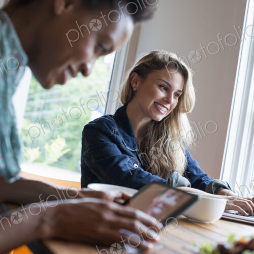 Two women in a cafe. Using a digital tablet and laptop. Working and keeping in touch. Two women in a cafe. Using a digital tablet and laptop. Working and keeping in touch.