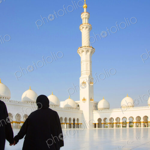 Two women in a mosque courtyard of colonnades, minaret and domes. Two women in a mosque courtyard of colonnades, minaret and domes.