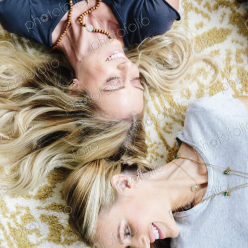 Two women lying on their backs, laughing.
