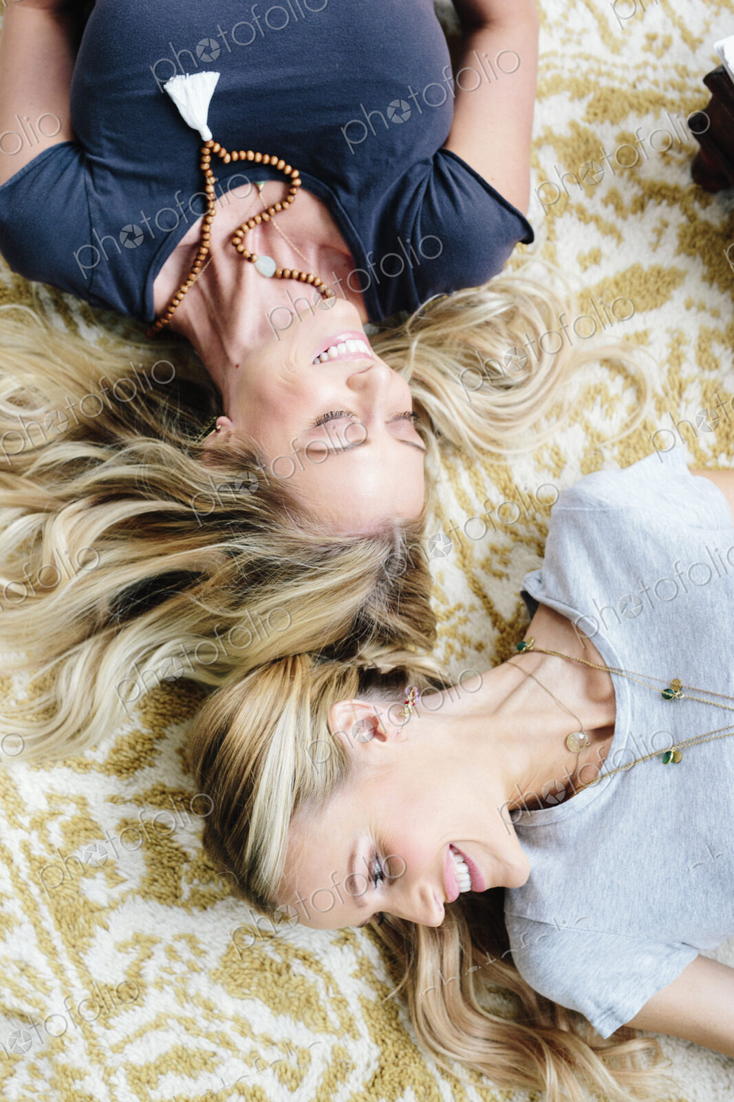 Two women lying on their backs, laughing.
