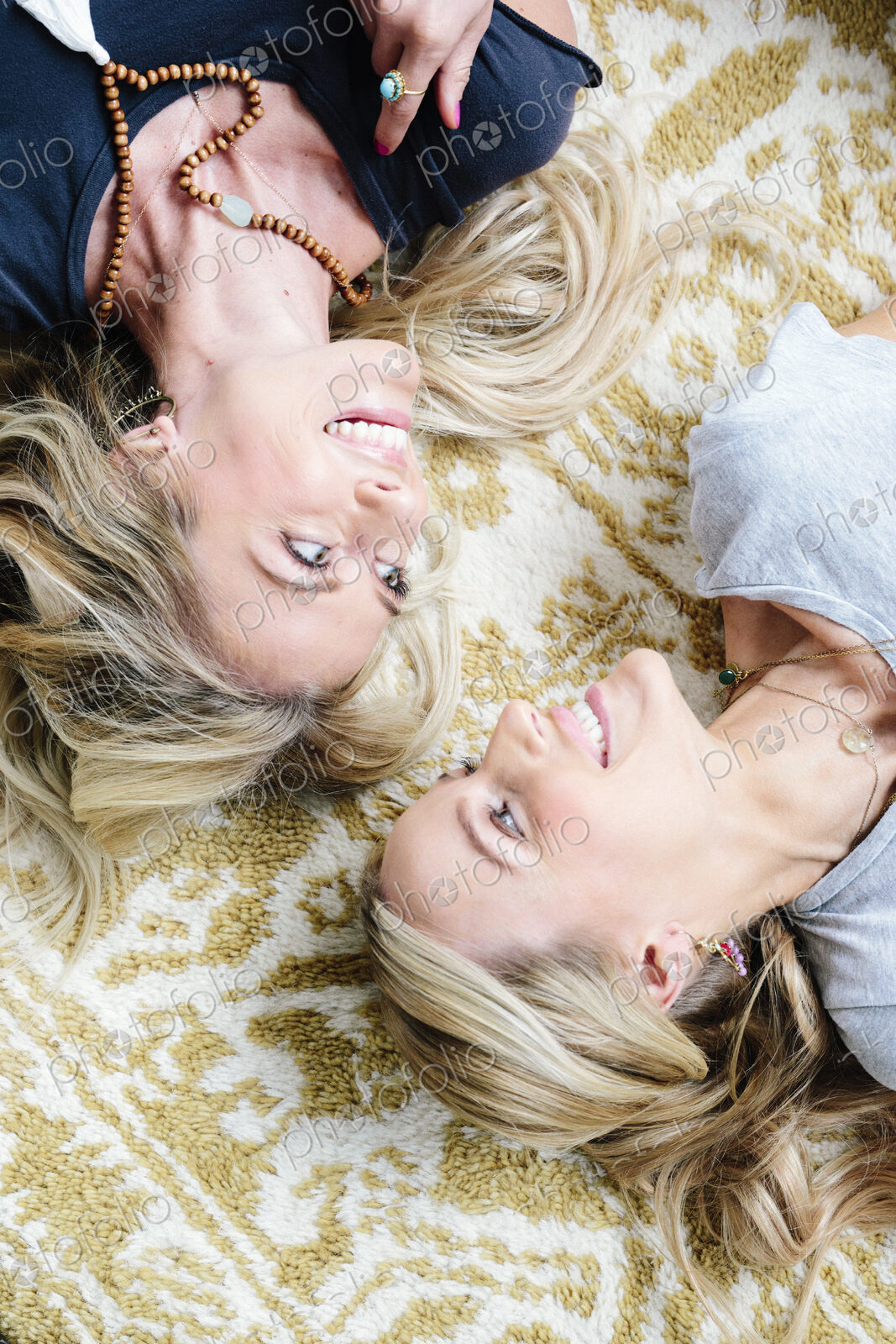 Two women lying on their backs looking at each other and laughing.