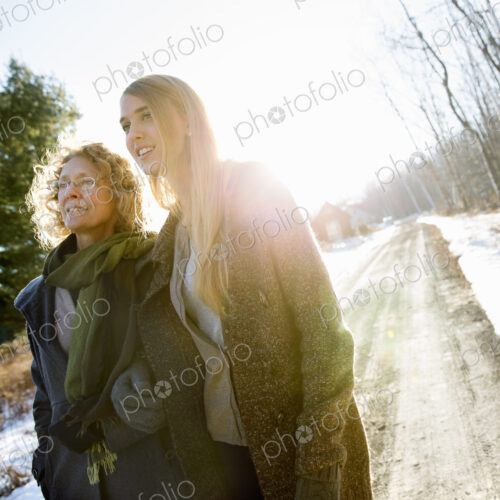 Two women, mother and adult daughter outdoors on a winter's day, snow on the ground.