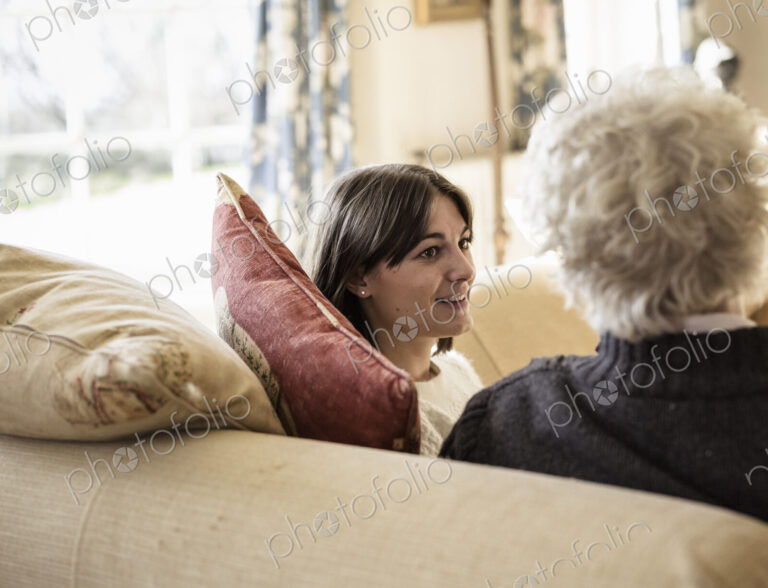 Two women, mother and daughter, sitting side by side, laughing.