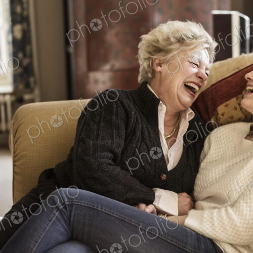 Two women, mother and daughter, sitting side by side, laughing. Two women, mother and daughter, sitting side by side, laughing.
