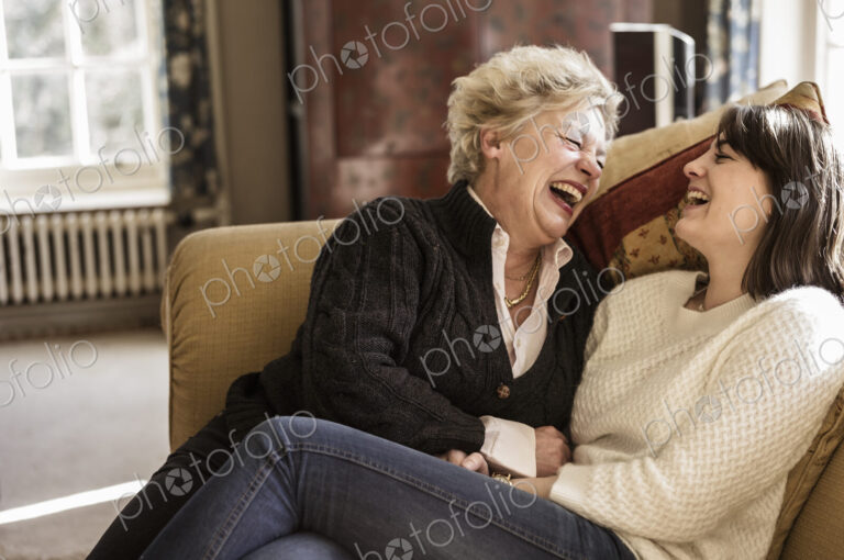 Two women, mother and daughter, sitting side by side, laughing.