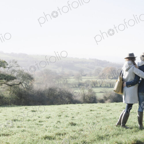 Two women side by side on a grass slope overlooking the landscape of Dorset. Two women side by side on a grass slope overlooking the landscape of Dorset.