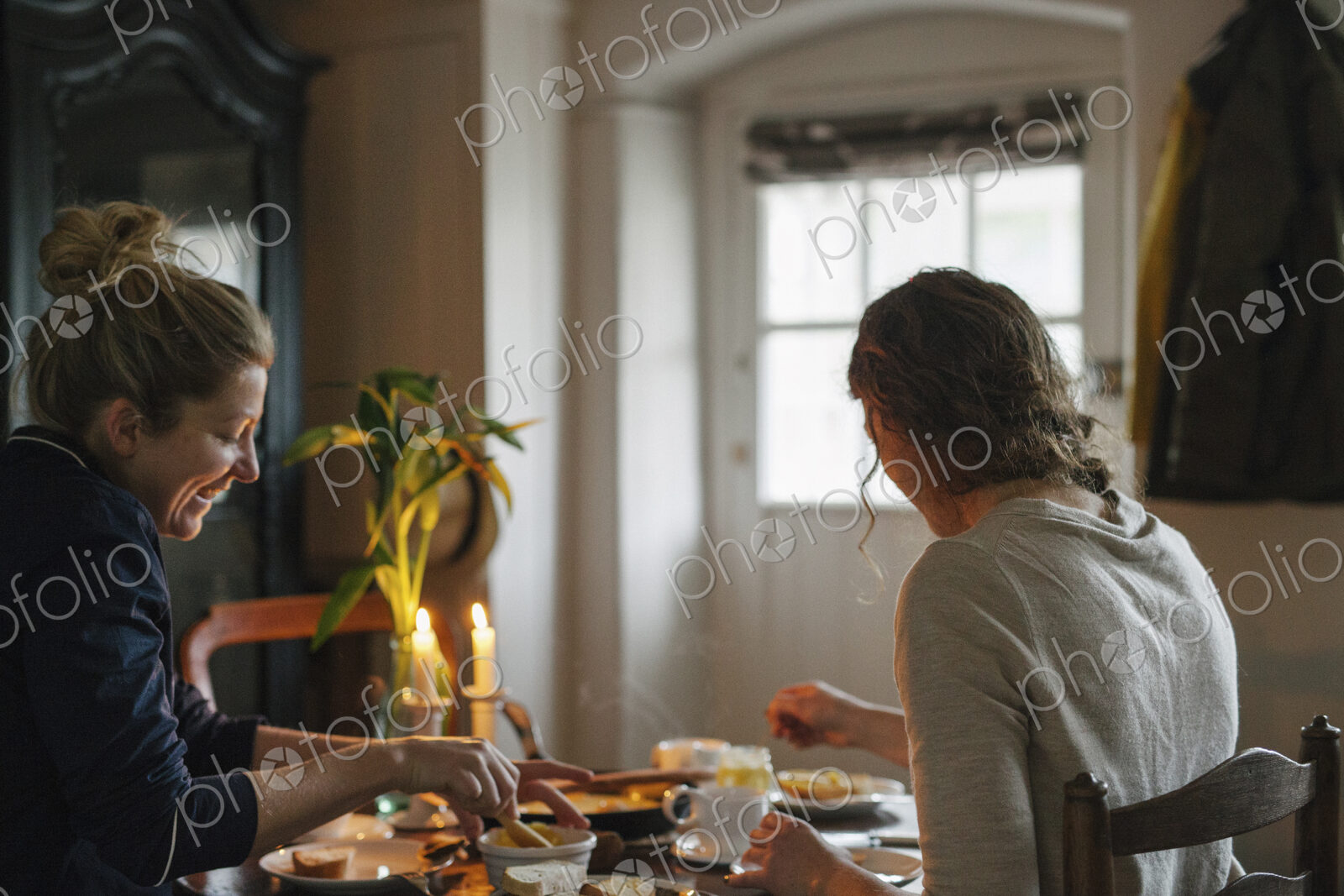 Two women sitting at a table having a meal by candlelight.