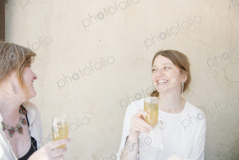 Two women sitting at a table, smiling at each other, holding glasses of champagne.