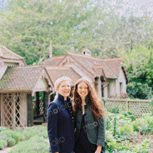 Two women standing in a garden of a historic house. Two women standing in a garden of a historic house.