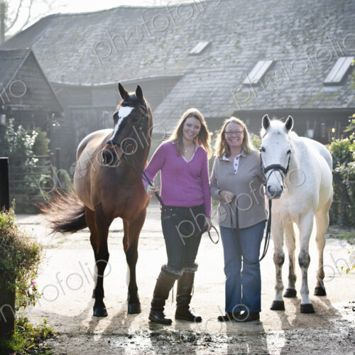 Two women standing outside a stable with two horses. Two women standing outside a stable with two horses.