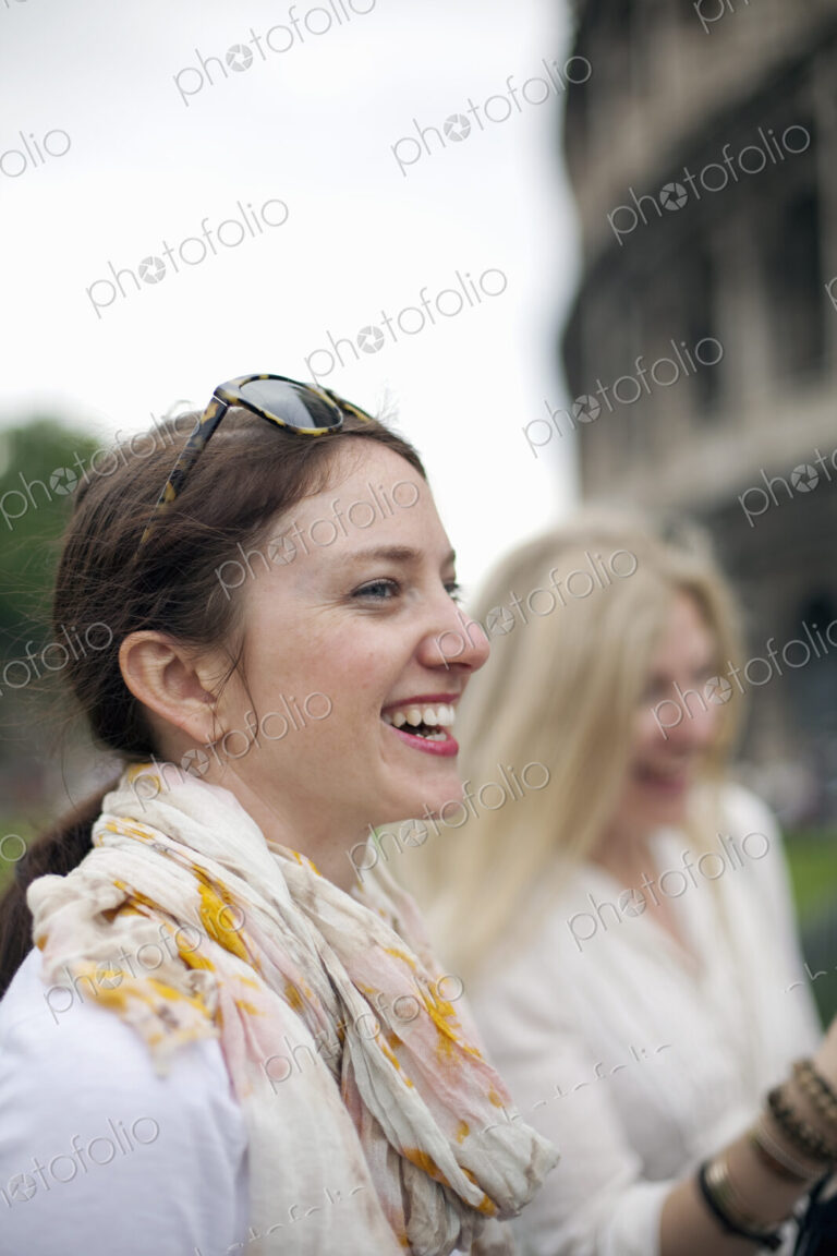 Two women standing outside the Colosseum Roman amphitheatre in Rome, side by side.…