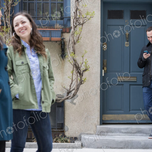 Two women talking as they walk down a street. A man leaning against a house door… Two women talking as they walk down a street. A man leaning against a house door…