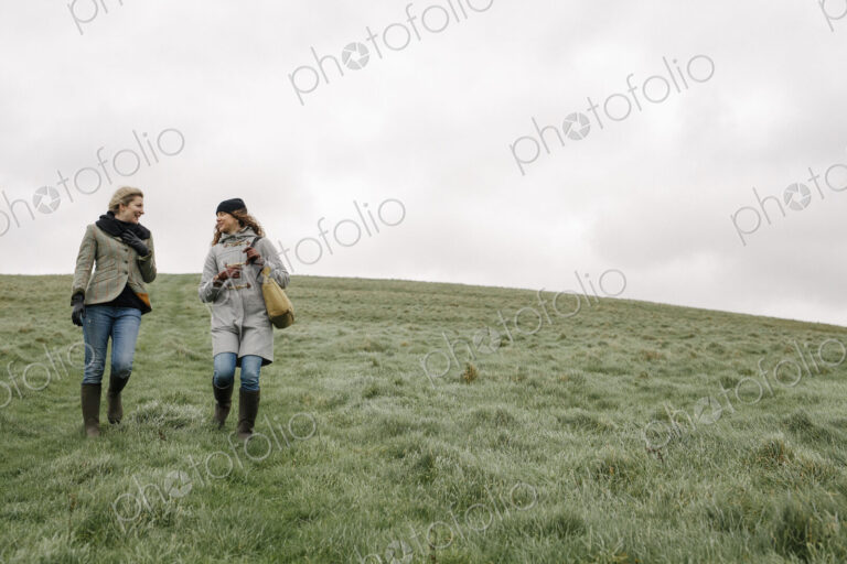 Two women walking across grass.