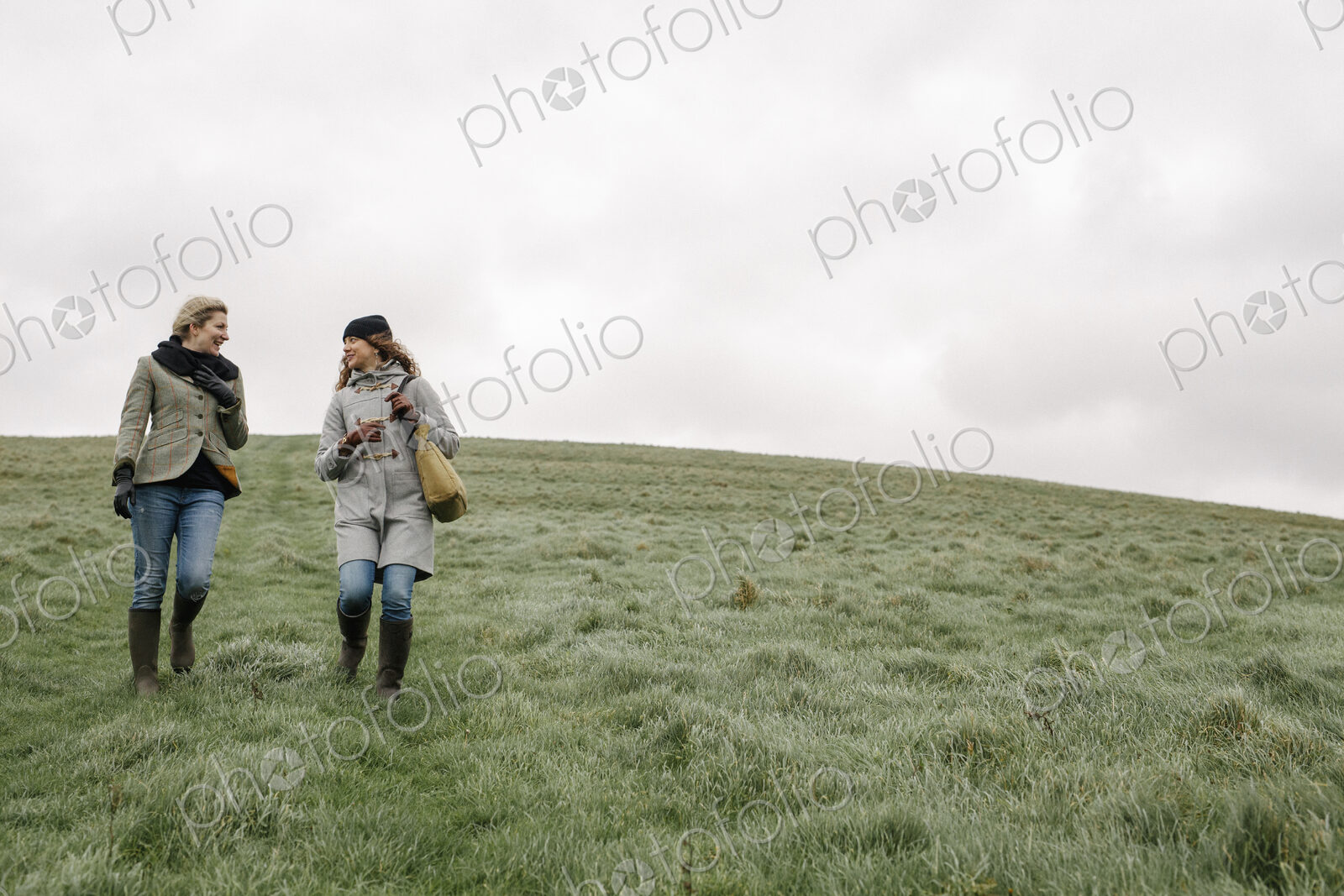 Two women walking across grass.