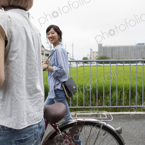 Two women walking along a footpath, pushing a bicycle.