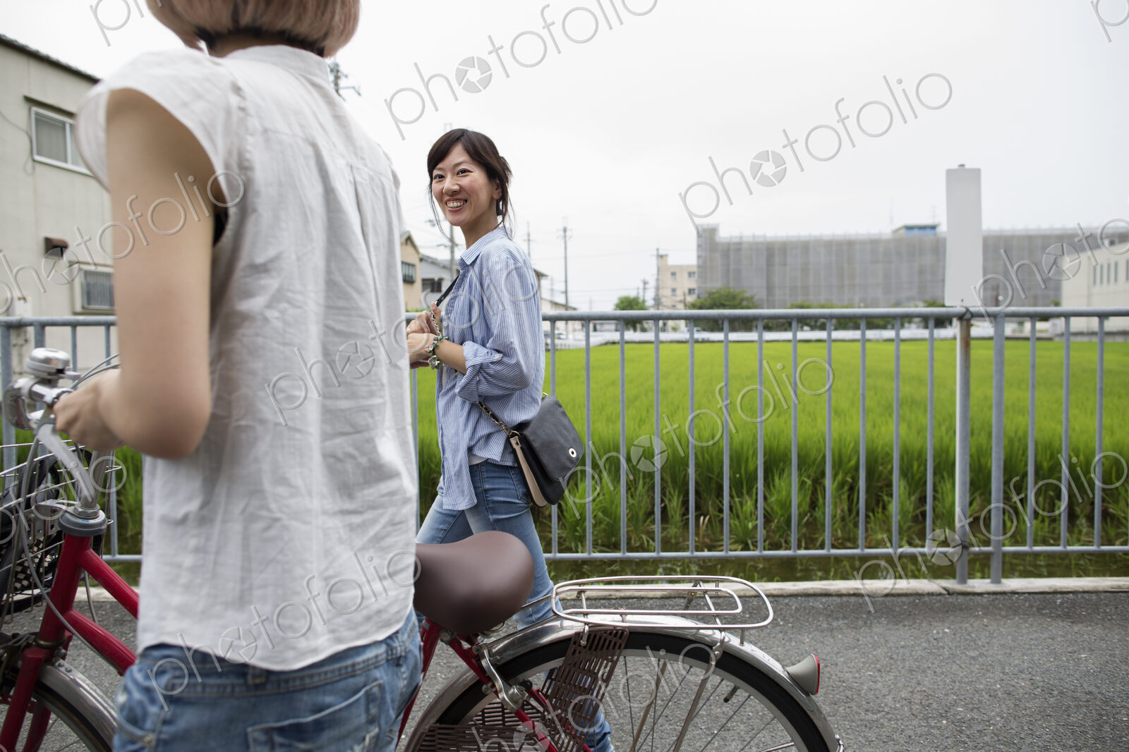 Two women walking along a footpath, pushing a bicycle.