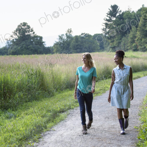 Two women walking down a path lined with trees.