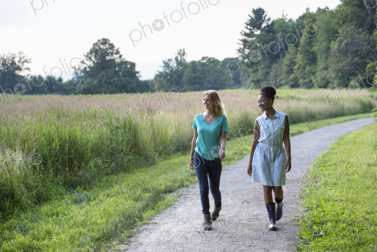 Two women walking down a path lined with trees.