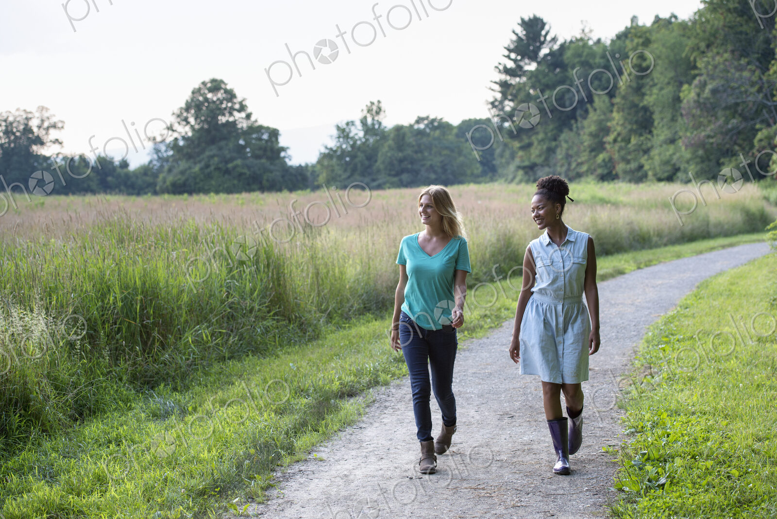 Two women walking down a path lined with trees.