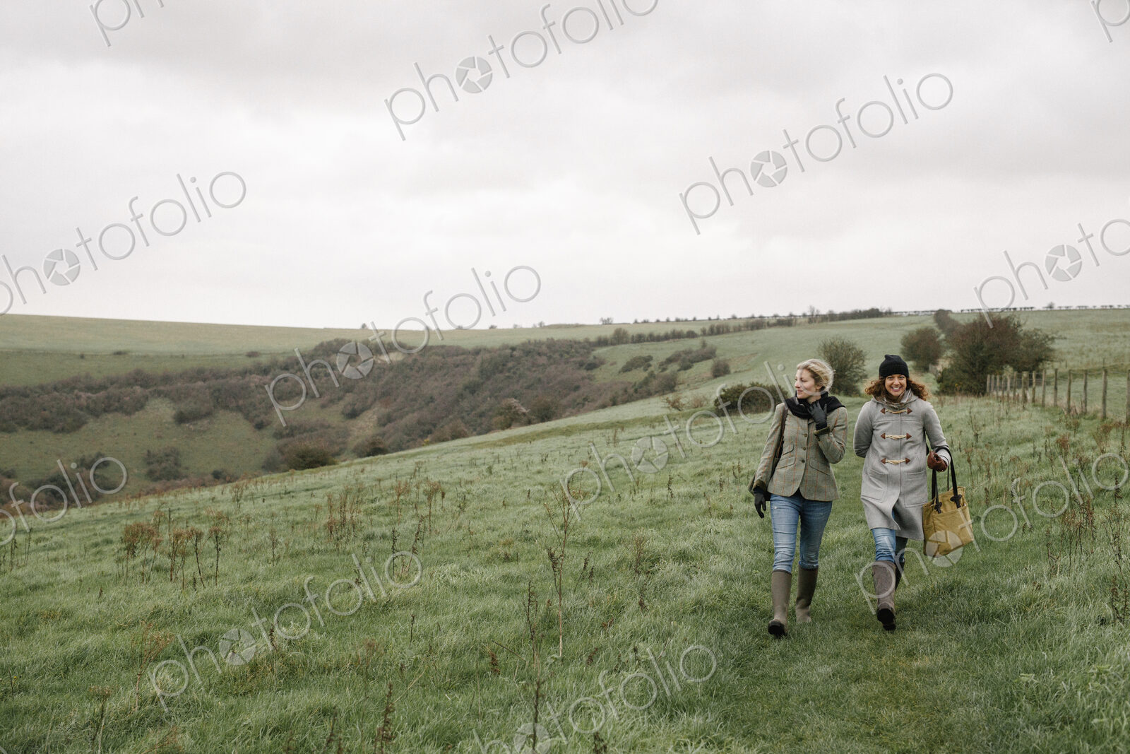 Two women walking on a country path across grassland.