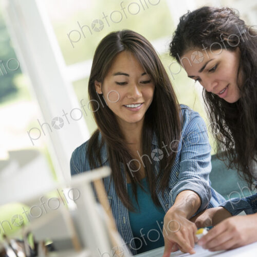Two women working together, looking at the screen of a digital tablet.