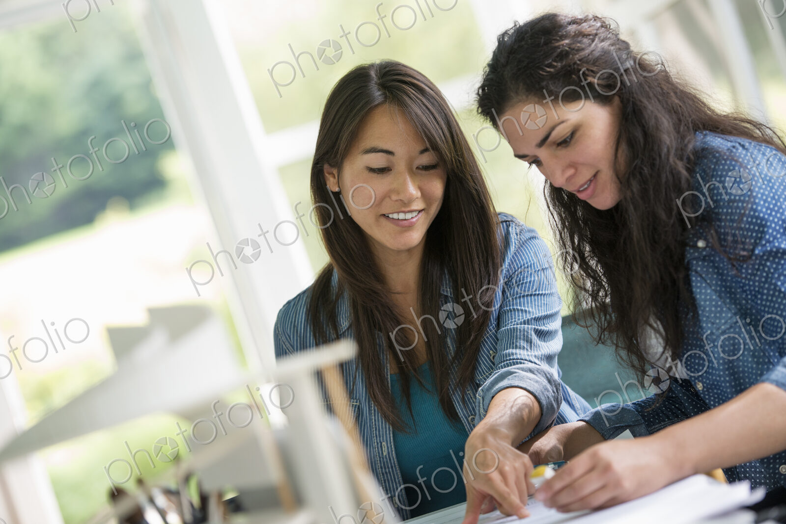 Two women working together, looking at the screen of a digital tablet.