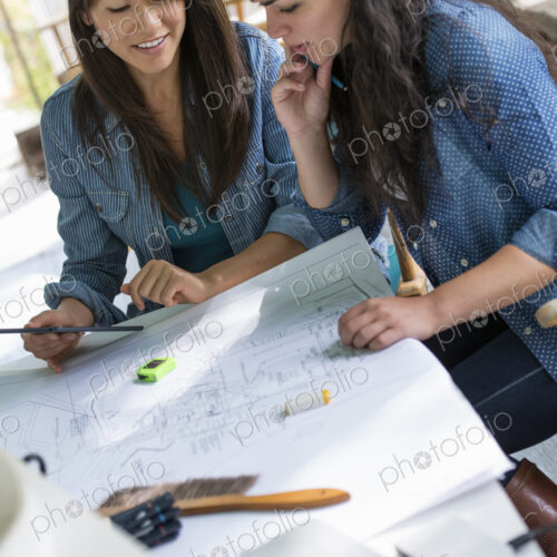 Two women working together, looking at the screen of a digital tablet.