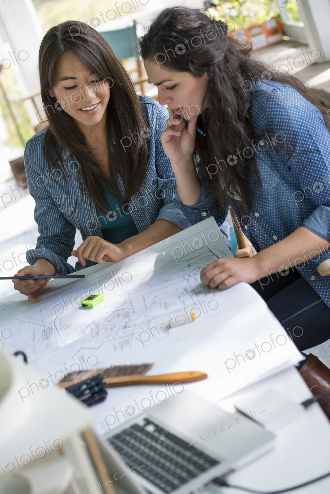 Two women working together, looking at the screen of a digital tablet.